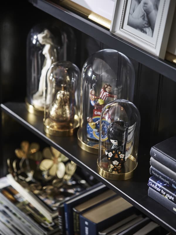 Four glass domes on a shelf containing various figures and ornaments.