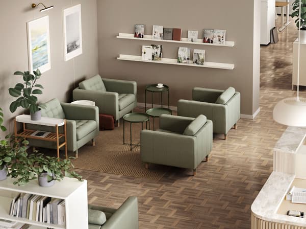 Four green LANDSKRONA armchairs with GLADOM tray tables between them. A MOSSLANDA picture ledge holds journals on the wall.