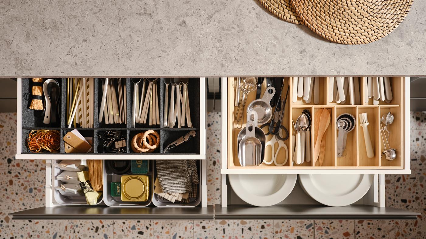 Four pulled-out MAXIMERA kitchen drawers with various items in a cutlery tray, an adjustable organiser for drawer and boxes.