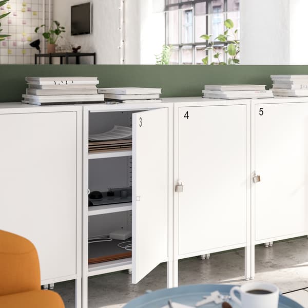 Four white lockable cabinets with numbers on them, one door is open showing three shelves and papers organised inside.