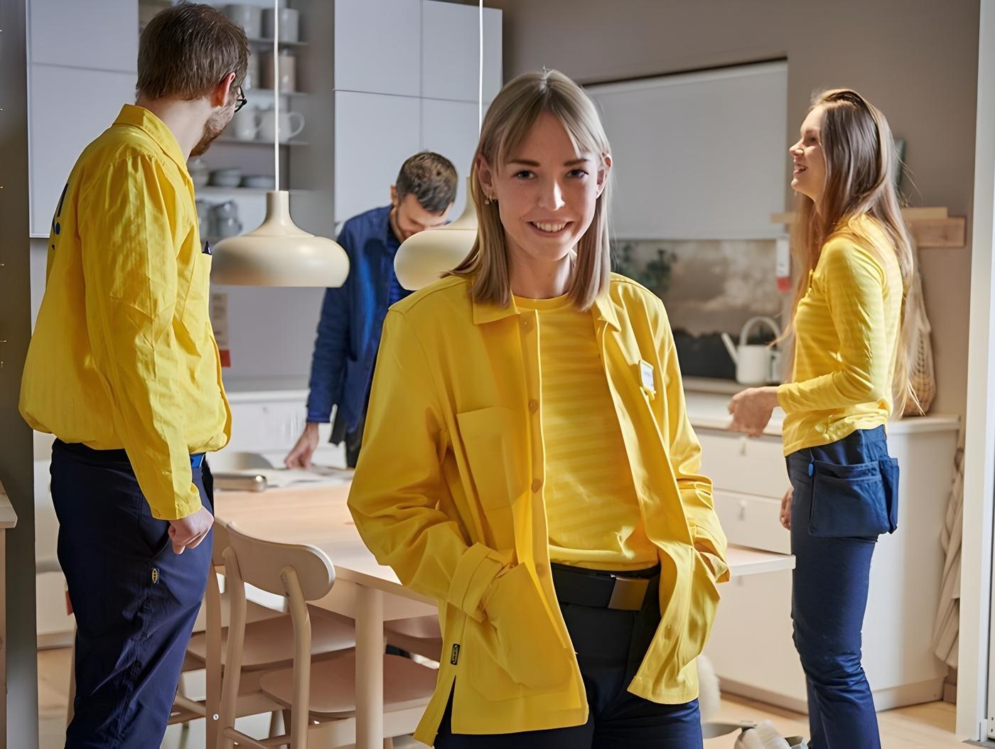Fyra personer med IKEA kläder som står runt ett bord i ett varuhus.
