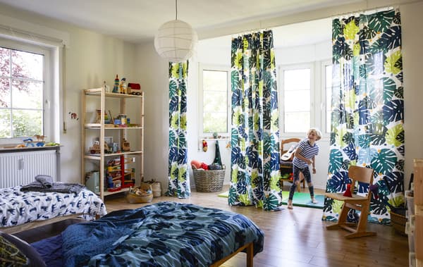 Garçon en train de jouer dans une chambre à coucher décorée de textiles sur le thème de la jungle.
