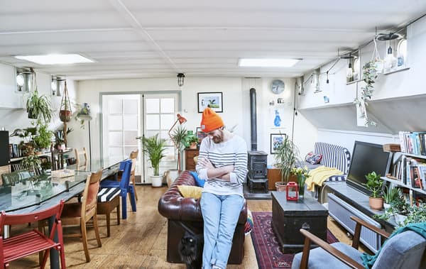 Gareth debout dans son séjour, avec une grande table à manger d’un côté et le coin salon de l’autre.