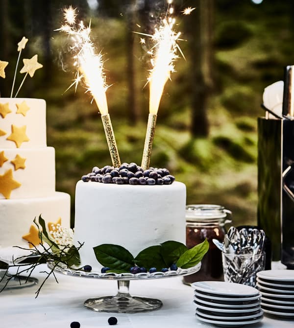 Gâteau de mariage blanc sur un plat sur pied, avec deux grands feux de bengale 