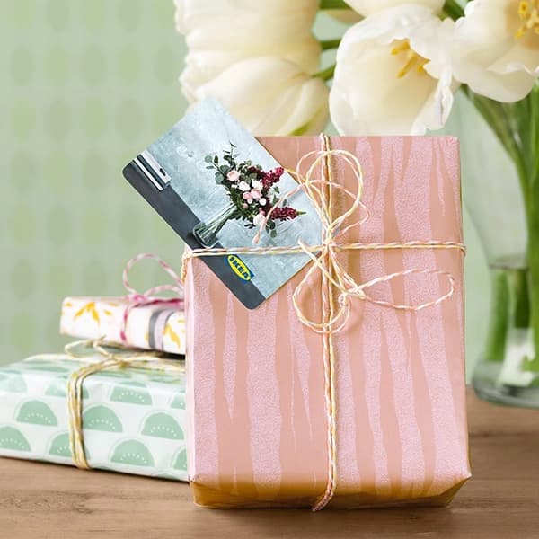 Gift wrap in a light pink paper with gift card added under the ribbon.
