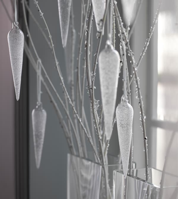 Glass ornaments hang from twigs in a window.