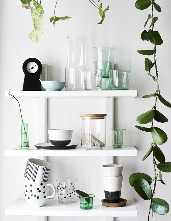 Glasses, mugs and plant cuttings displayed on three white shelves.