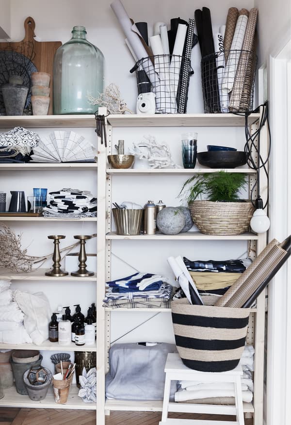 Glassware, textiles and plants on open shelves.