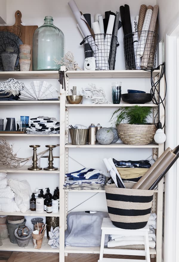 Glassware, textiles and plants on open shelves.