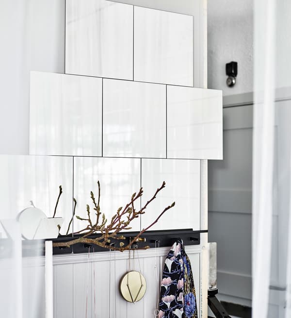 Glossy white tiles mounted onto a white wall and reflecting natural light to brighten up the airy bedroom.