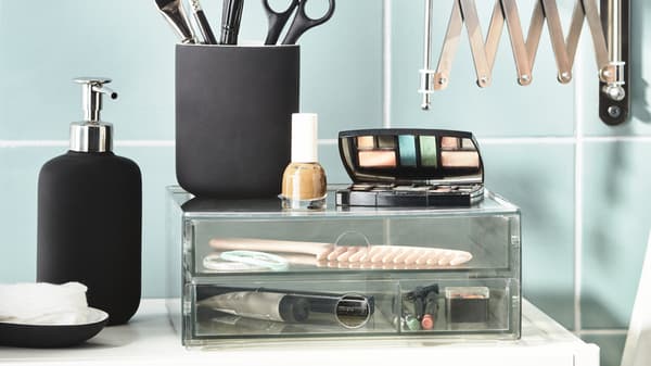 GODMORGON mini chest of 2 drawers with EKOLN toothbrush holder and soap dispenser placed next to and on top of it. Cosmetic products and items are stored neatly inside and on top of the drawers.  
