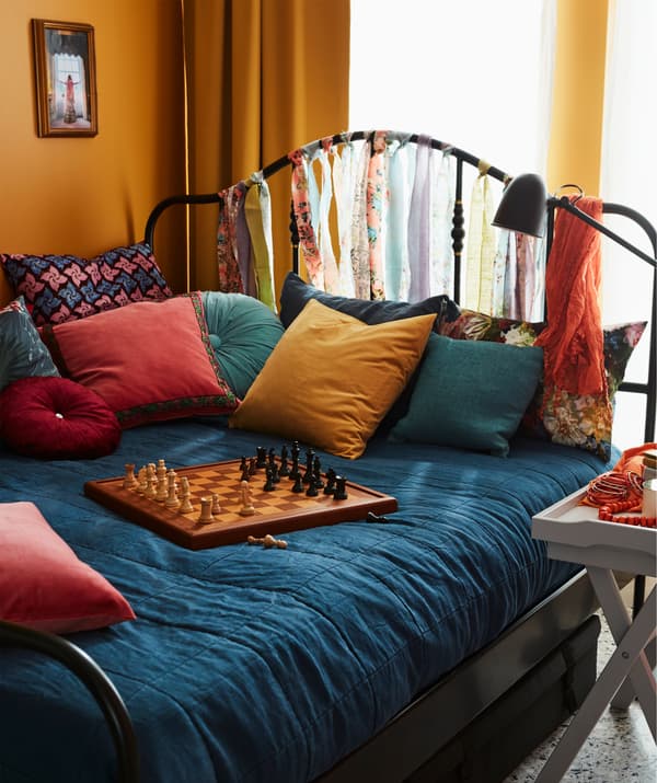 Grand lit garni de nombreux coussins, jeu d’échec posé sur la couette. Une table-plateau placée à proximité accueille boissons et collations.