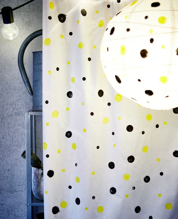 Grand morceau de tissu orné de pois peints, utilisé pour cacher une étagère métallique dans un garage.
