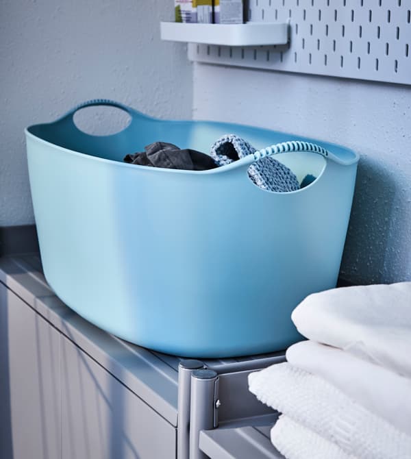 Grand panier à linge bleu posé sur une armoire.