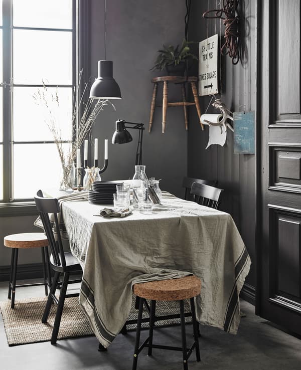 Grande table de salle à manger couverte de documents, avec nappe en lin et assiettes couvrant le reste.