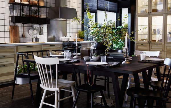 Grande table en bois foncé avec plein de chaises au milieu d'une cuisine suédoise moderne.