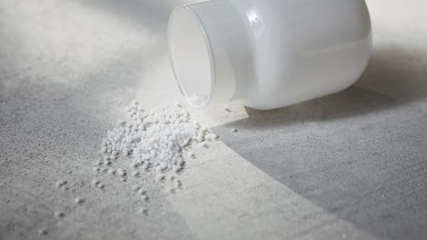 Granules synthétiques sortant d’un contenant en verre sur du tissu. 