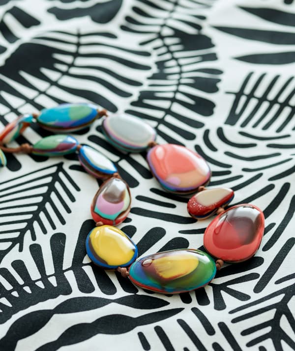 Graphic black and white fabric with a necklace made of spherical-shaped links in different colors on top.