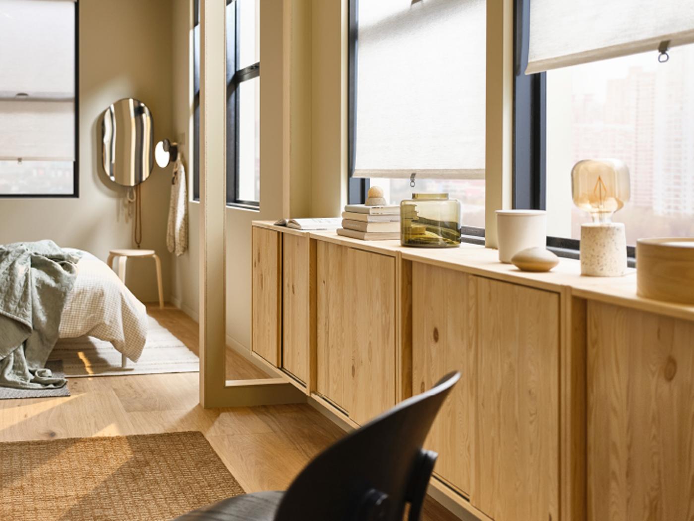 Grenen IVAR kast met schuifdeuren en daarop verschillende voorwerpen, in een lichtgekleurde slaapkamer met SANDVEDEL rolgordijnen voor het raam.