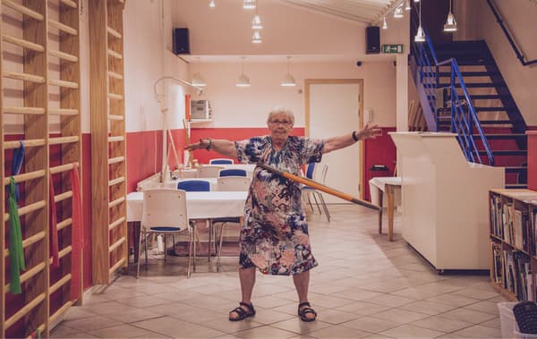Greta dances with a hula hoop in a dining room with red and white walls.