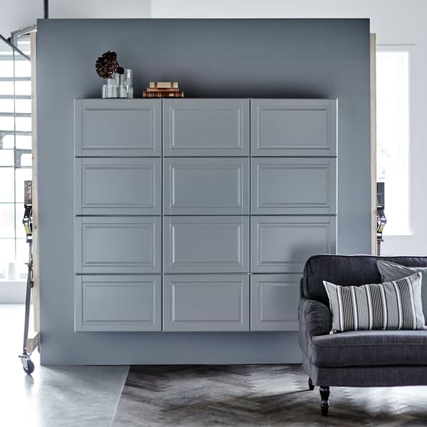 Grey METOD cabinets against a grey wall with a sofa in front.