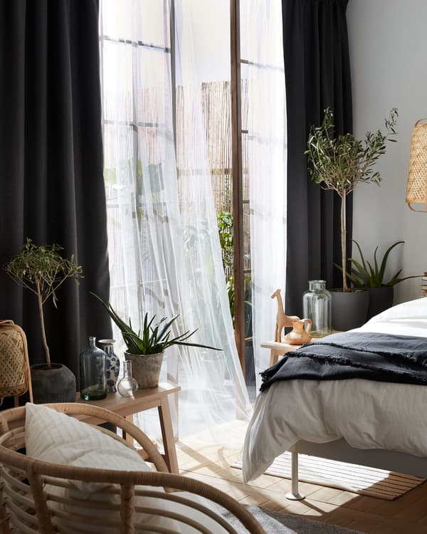 Grey room darkening curtains combined with sheer white curtains, a BUSKBO armchair and olive trees in pots.