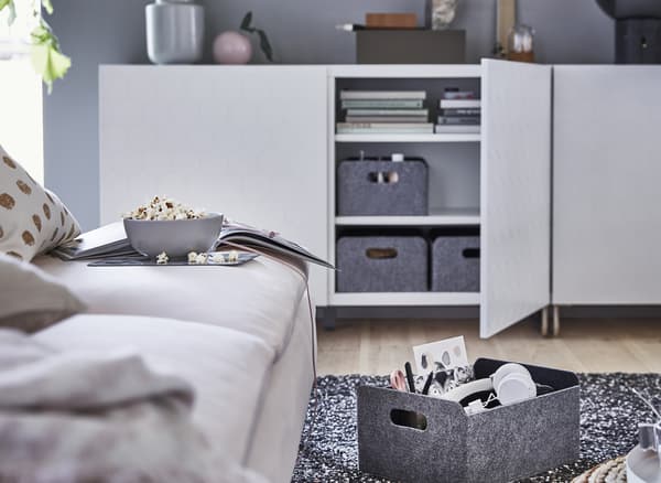Grey storage boxes inside a low white storage unit.