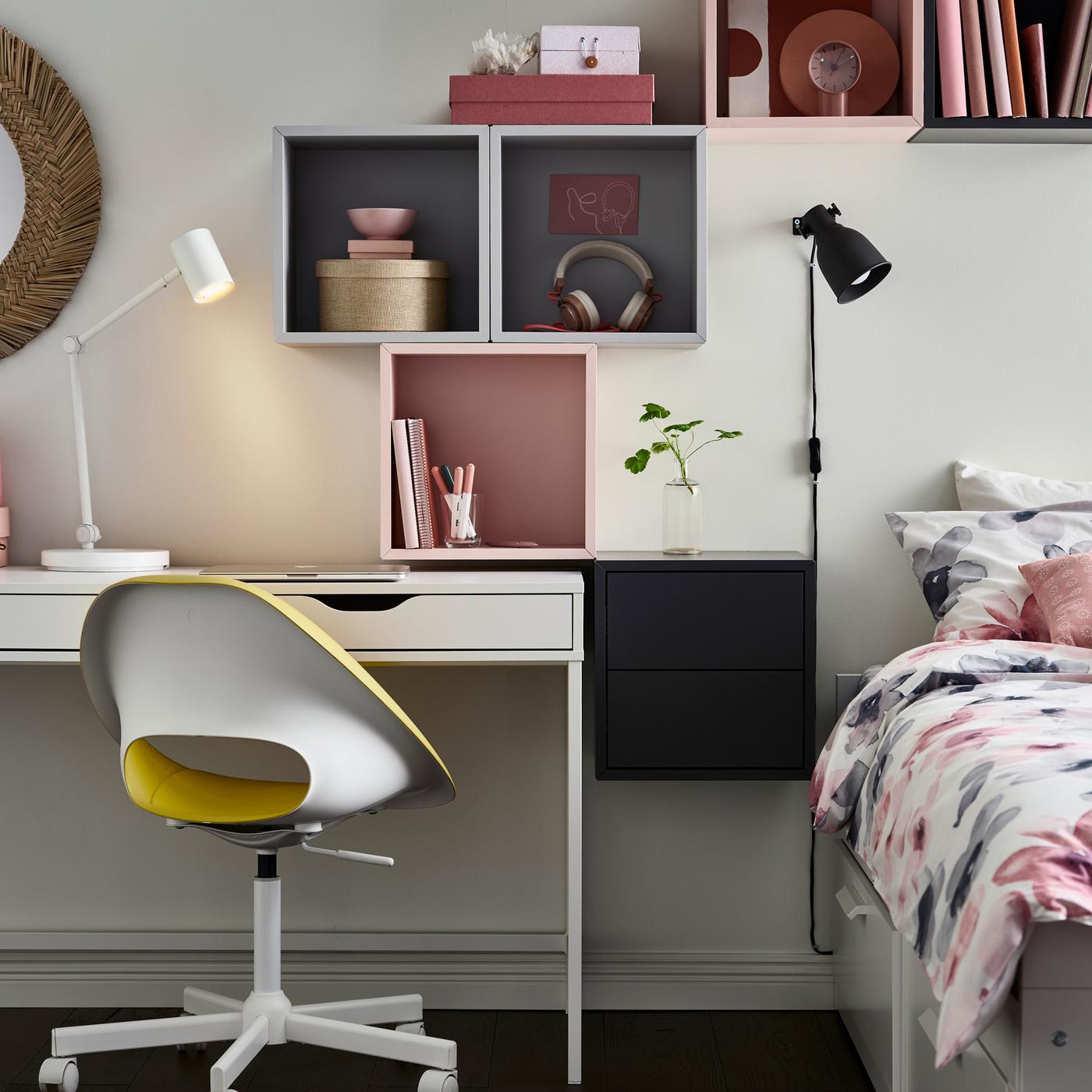 Grijze en roze EKET kasten boven een wit ALEX bureau en een witte BRIMNES bedbank met veelkleurig LAPPNYCKLAR beddengoed.