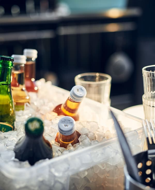 Gros plan de boissons disposées dans un bac en plastique rempli de glace.
