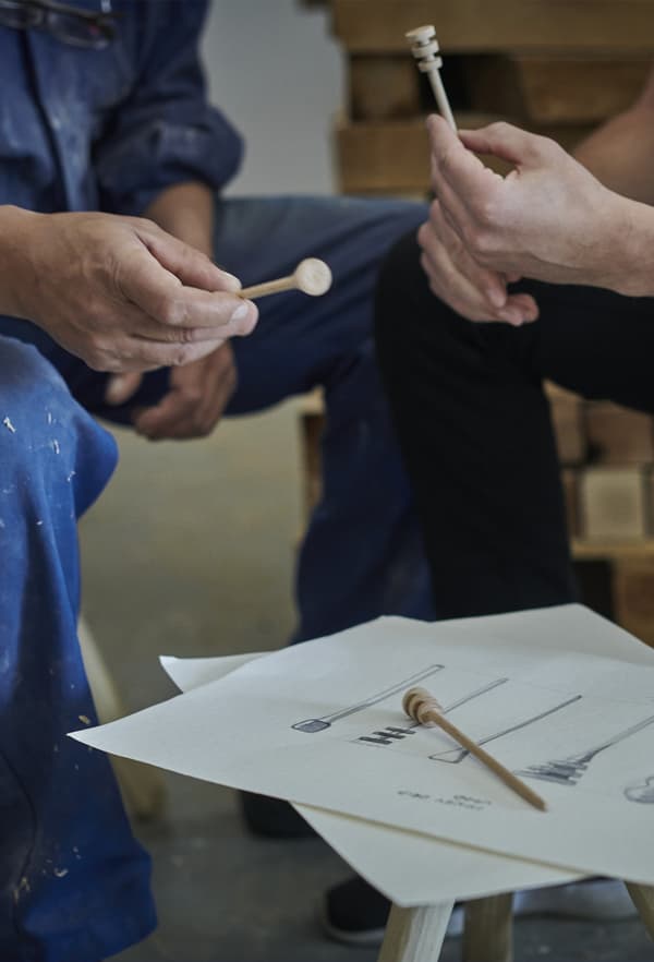 Gros plan de deux hommes tenant en main des produits en bois en cours de développement dans un atelier.