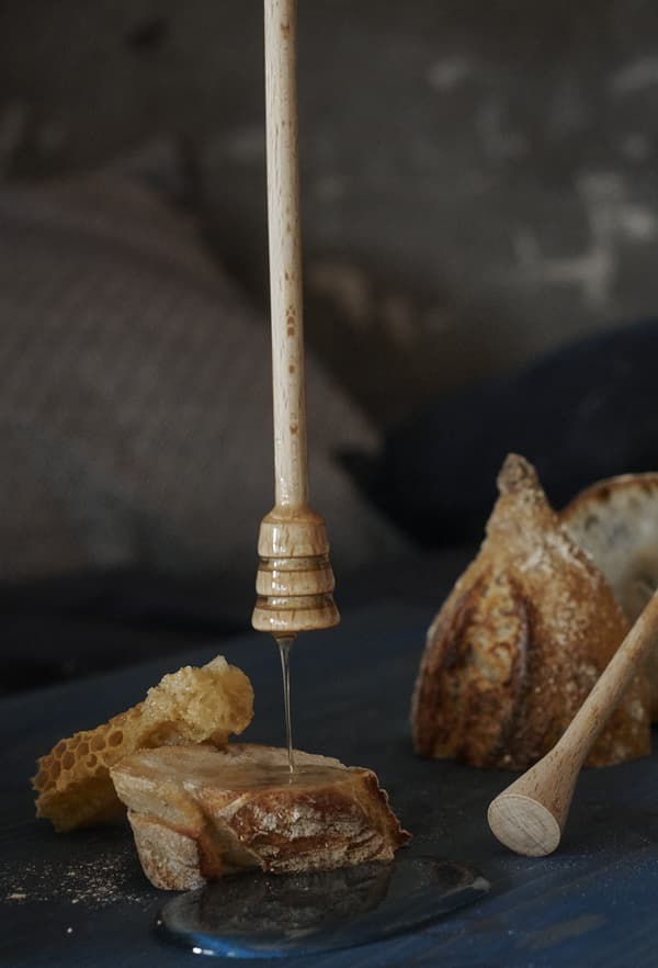 Gros plan de miel s’écoulant d’un bâton à miel sur des morceaux de pain.