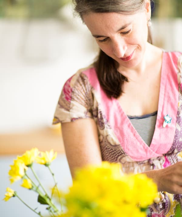 Gros plan d’Edna arrangeant des fleurs jaunes.