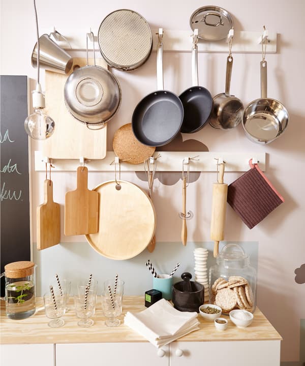 Gros plan du mur, montrant les casseroles, poêlons et ustensiles de cuisine pendus à des crochets.