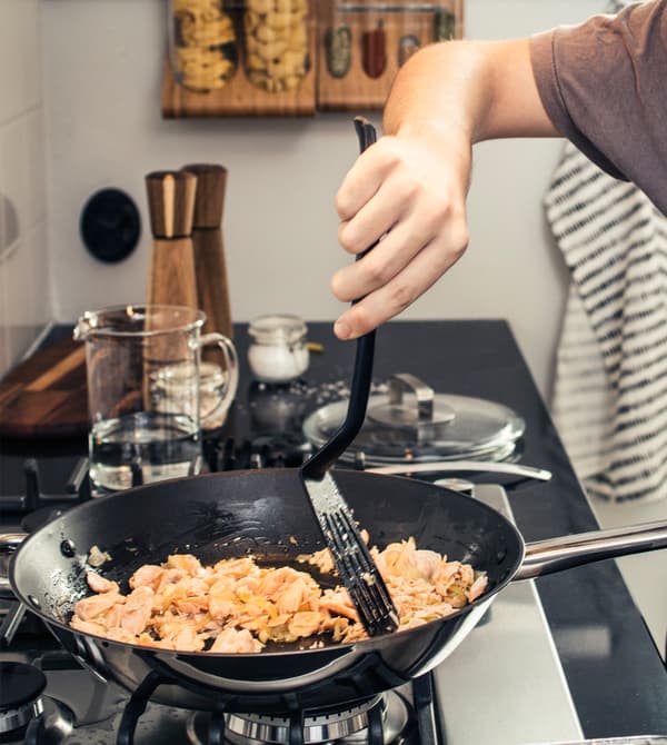 Gros plan d'un ado en train de remuer des aliments dans une poêle