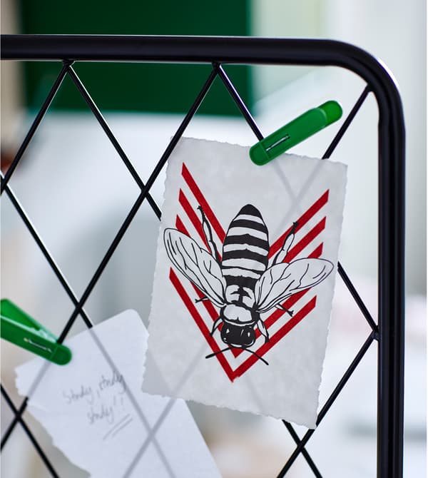 Gros plan d’un grand treillis métallique noir avec des dessins et des messages clipsés dessus.