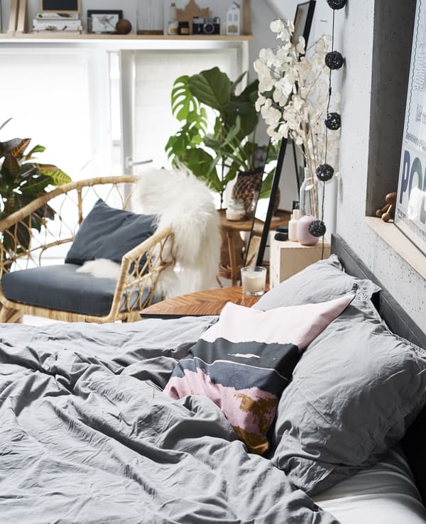 Gros plan d’un lit, avec fauteuil à l’arrière-plan.