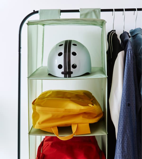 Gros plan d’un organiseur à suspendre, avec casque, sacs et pulls.