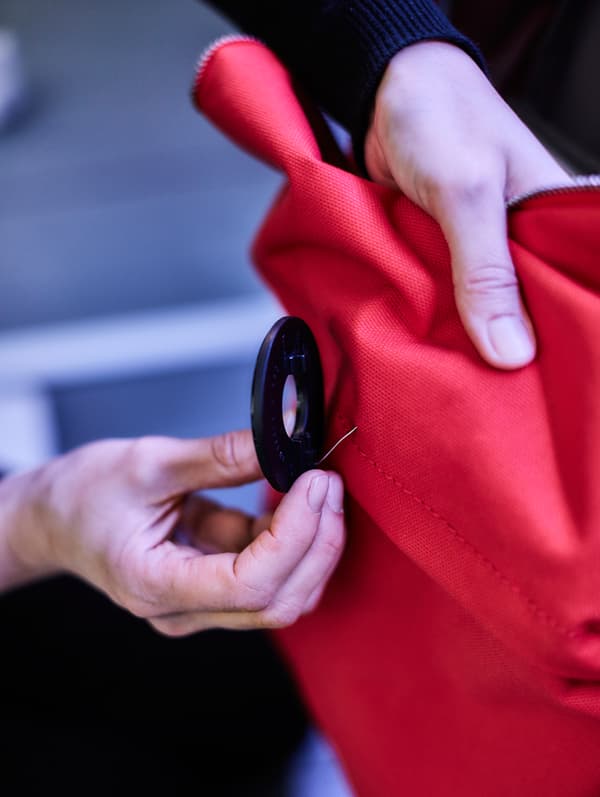 Gros plan d’une broche ronde réfléchissante fixée à un sac à dos rouge