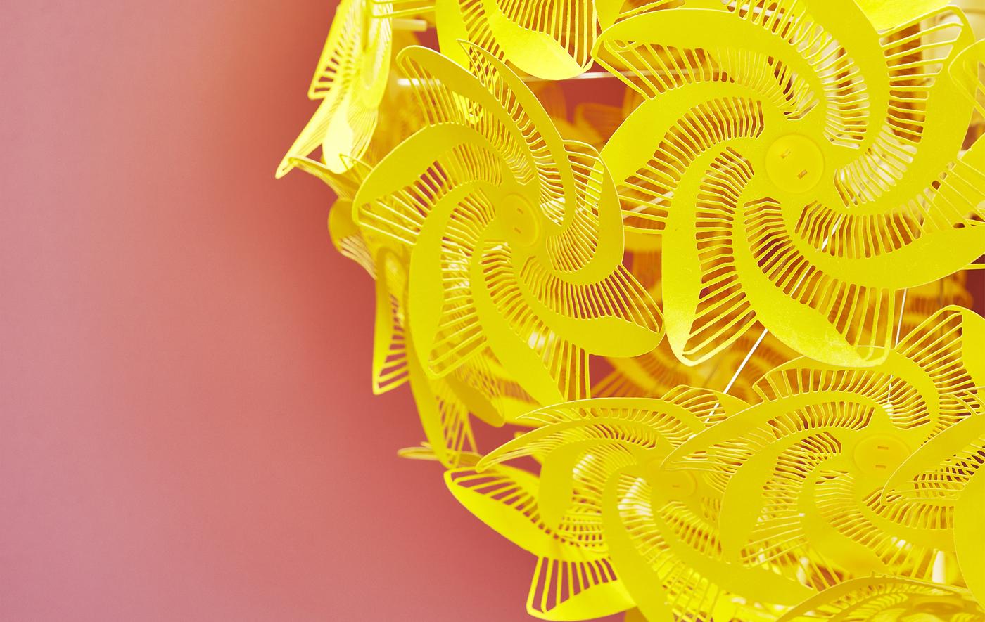 Gros plan d’une lampe jaune aux formes découpées sur fond rouge.
