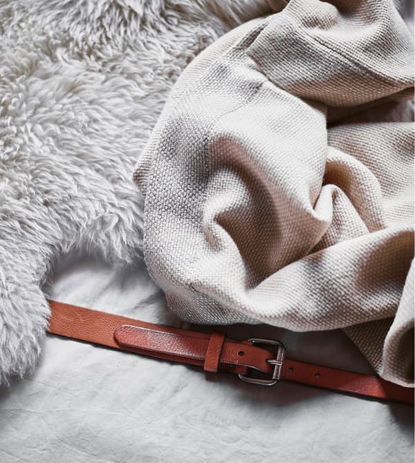 Gros plan d'une peau de mouton et d'un plaid moelleux posés sur le canapé composé de matelas.