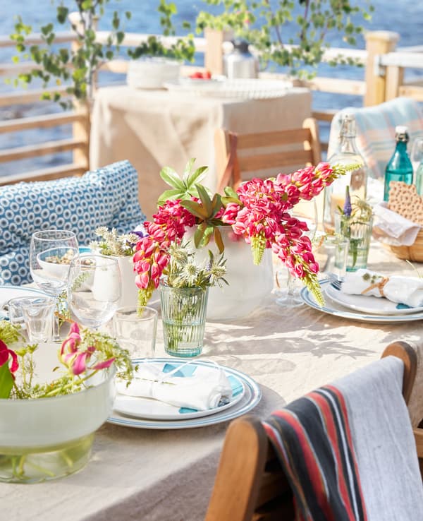 Gros plan d'une table dressée pour le repas, avec bouquet de fleurs, nappe et serviettes.