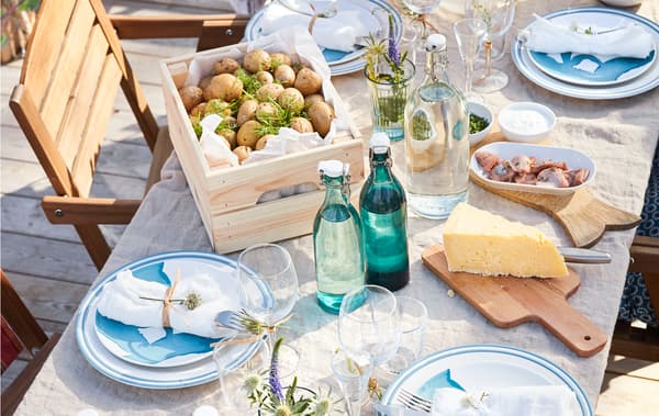 Gros plan d'une table dressée pour le repas, avec couverts, linge de table, fleurs et nourriture.