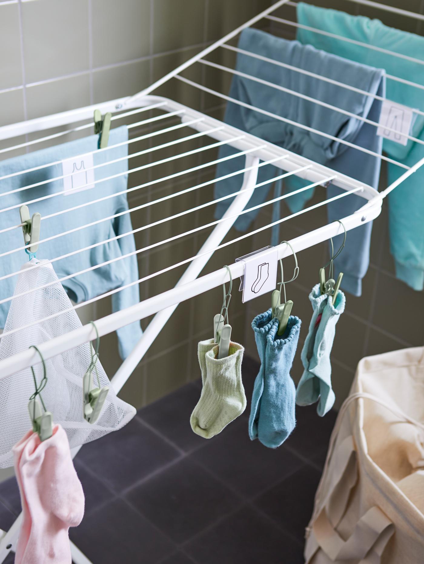 Gros plan sur un séchoir MULIG où des vêtements et des chaussettes de couleur sont suspendus à l’aide de pinces à linge SLIBB.