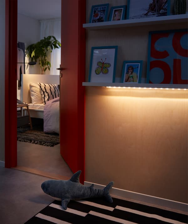 Hallway where an LED lighting strip illuminates the floor from under a picture ledge.