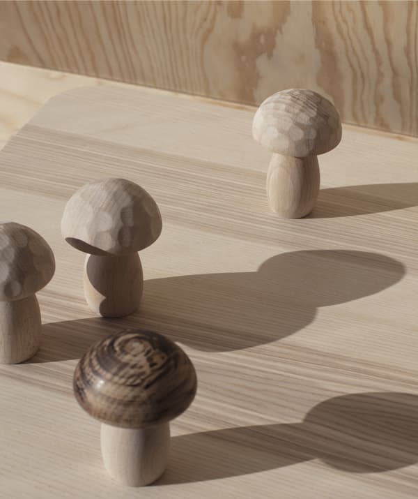 Hand-turned wooden mushroom shapes from the IKEA ANNANSTANS collection standing on a wooden surface.