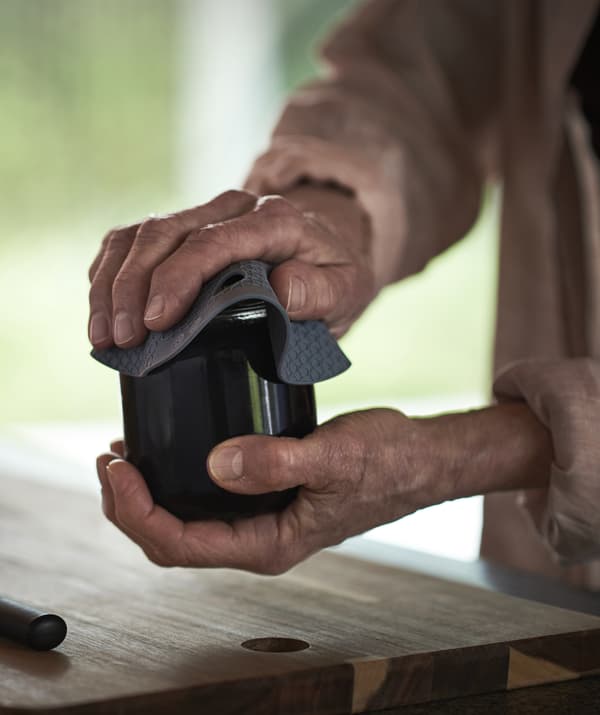Hands opening a jar using a silicone rubber gripper.