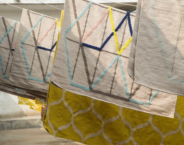Handwoven multicoloured IKEA PS rugs hanging in the sun.