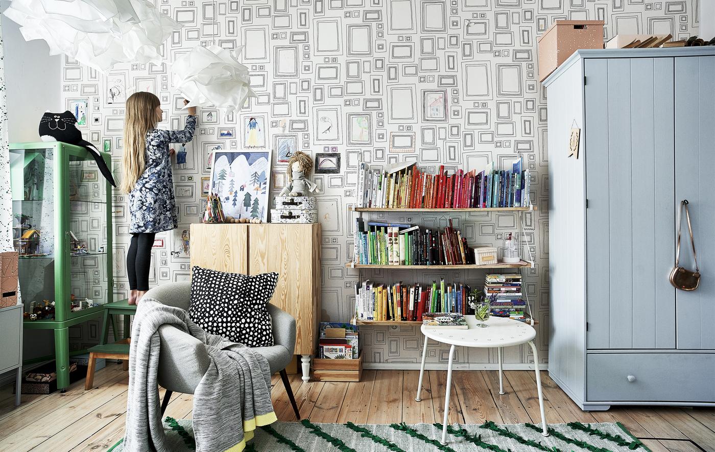 Hania nella sua cameretta arredata con mobili colorati, un tappeto verde e una libreria arcobaleno – IKEA