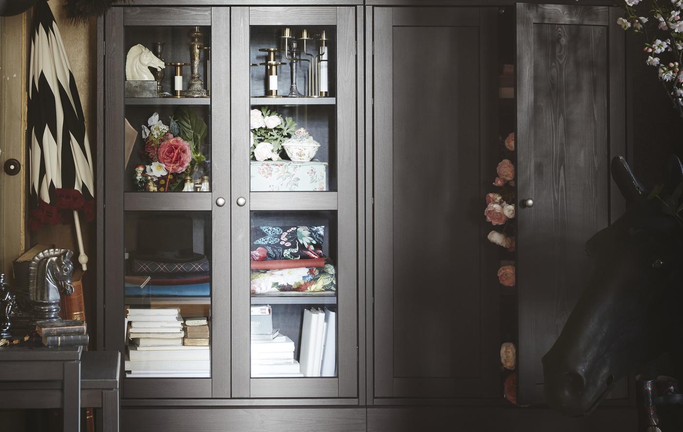 HAVSTA glass-door cabinet displaying flowers, books and candlesticks.