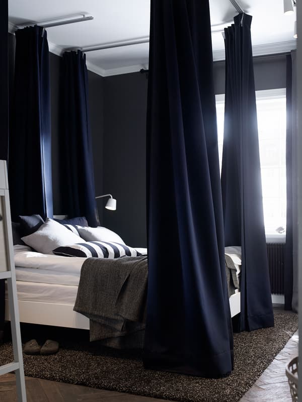 Heavy, dark blue curtains at the corners of this bed help dampen light and sound.